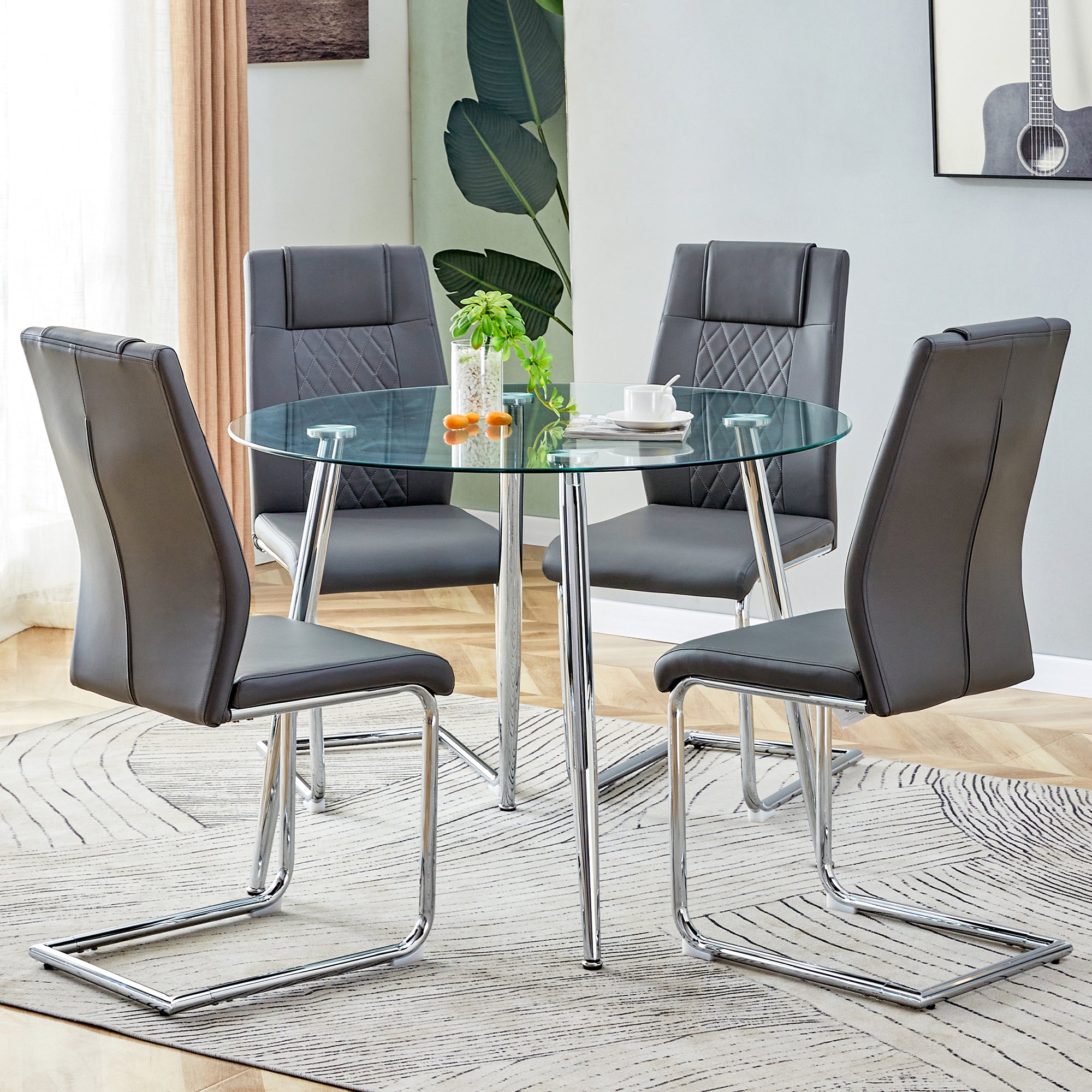 Table and chair set. (1 table+4 gray chairs) Round dining table with a 40 inch diameter glass tabletop and silver plated metal legs. 4 gray PU chairs DT-1164 001