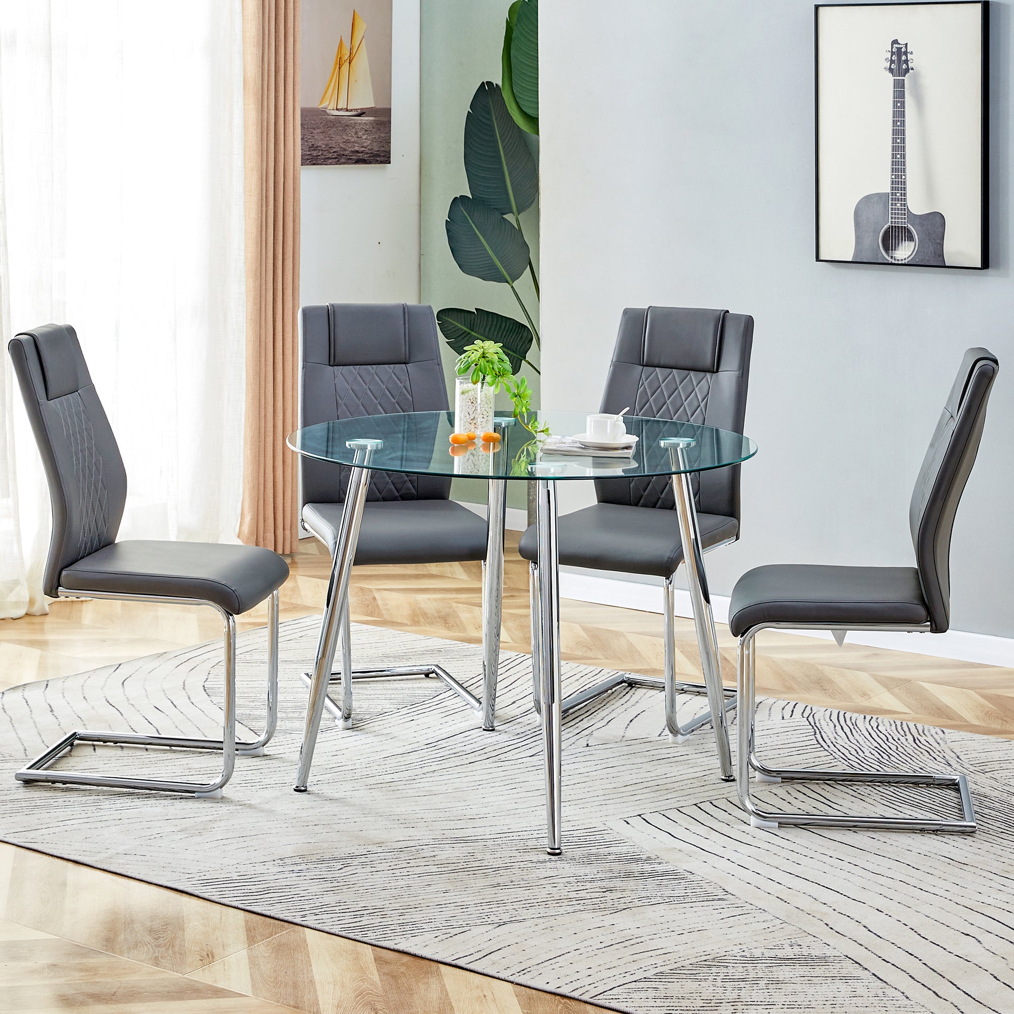 Table and chair set. (1 table+4 gray chairs) Round dining table with a 40 inch diameter glass tabletop and silver plated metal legs. 4 gray PU chairs DT-1164 001